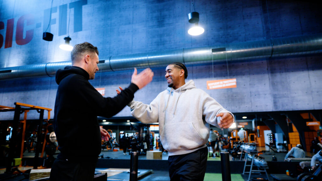 vrolijke begeleiders tijdens het sporten. ze zijn sporten met mensen die ze begeleiden. deze mensen zijn niet in beeld.